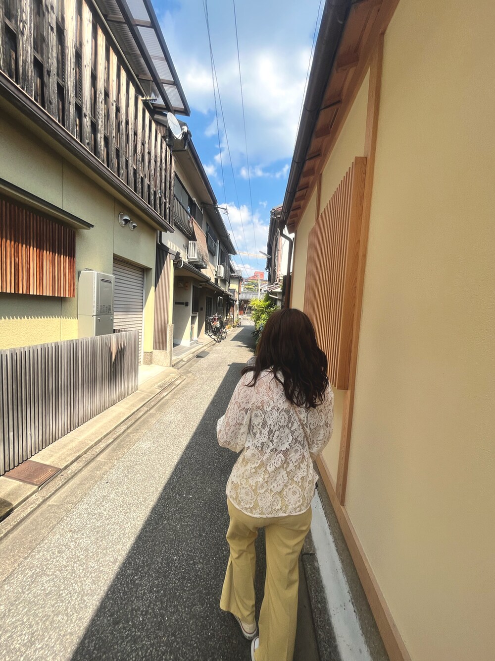 イエロー系のスラックス、ベージュ系のカーディガン/ボレロ、ベージュ系のスニーカーを着用したレディースの夏コーディネートの2枚目の写真