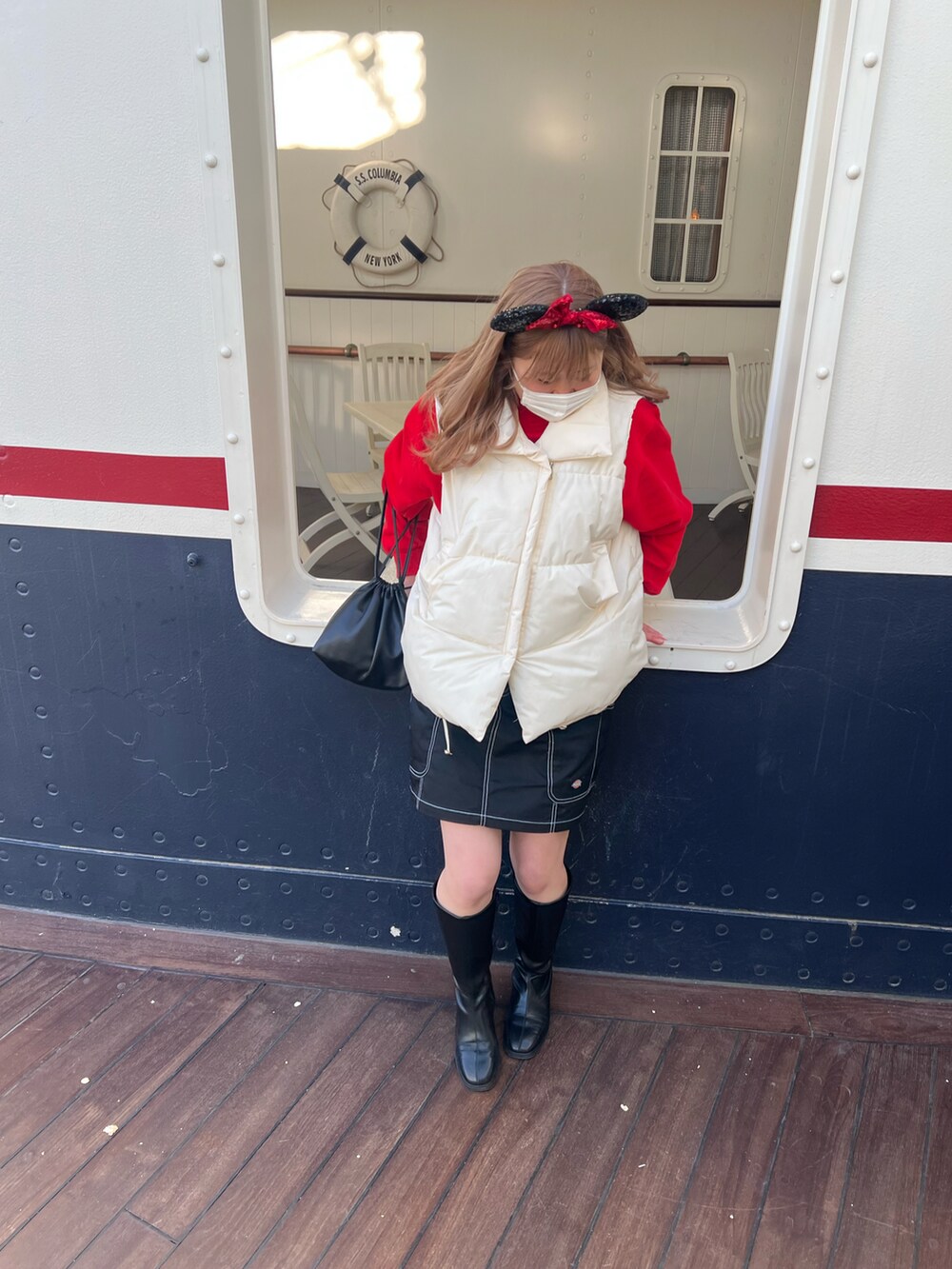 レッド系のスウェット、ブラック系のブーツ、ブラック系のスカートを着用したレディースの春コーディネートの2枚目の写真