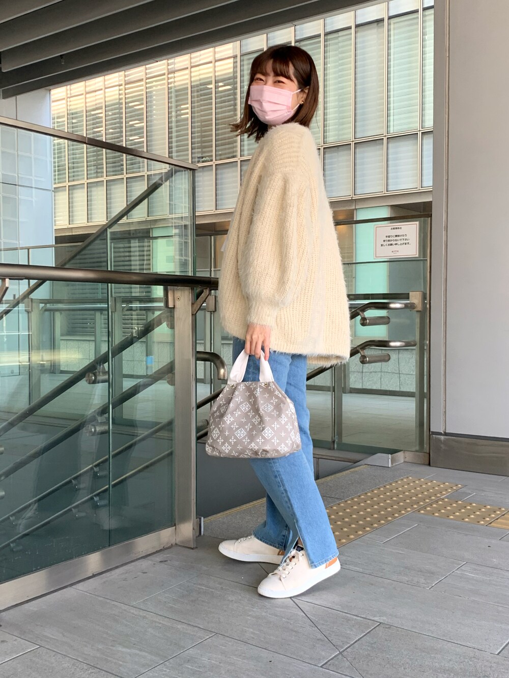 ホワイト系のスニーカー、ブルー系のデニムパンツ、ベージュ系のトートバッグを着用したレディースの春コーディネートの3枚目の写真