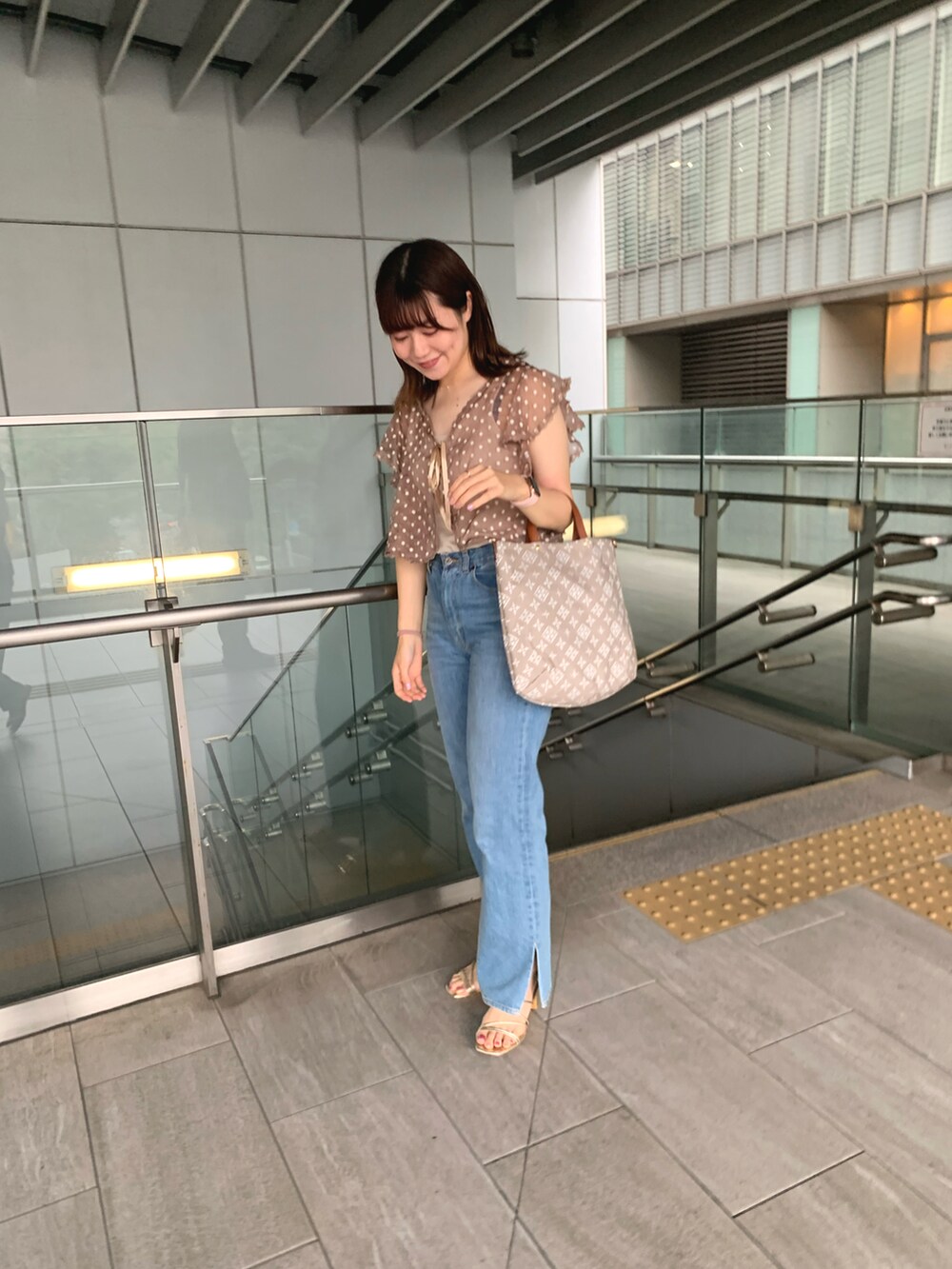 ブラウン系のシャツ/ブラウス、ブルー系のデニムパンツ、ベージュ系のトートバッグを着用したレディースの夏コーディネートの4枚目の写真