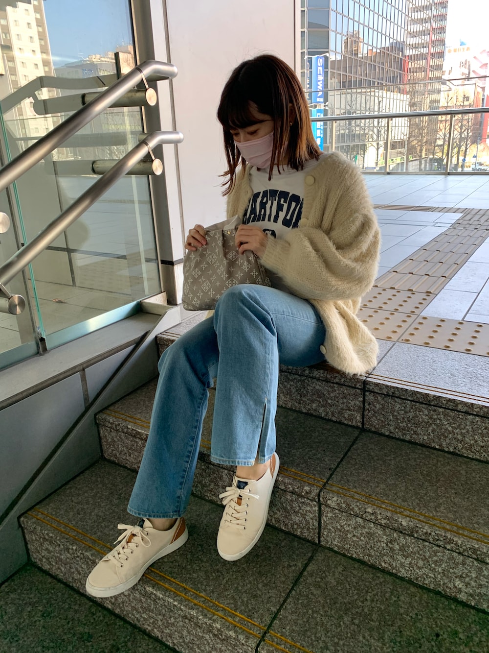 ホワイト系のスニーカー、ブルー系のデニムパンツ、ベージュ系のトートバッグを着用したレディースの春コーディネートの2枚目の写真