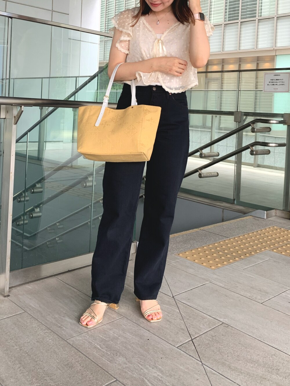 イエロー系のトートバッグ、ベージュ系のシャツ/ブラウス、ブラック系のチノパンツを着用したレディースの夏コーディネートの2枚目の写真