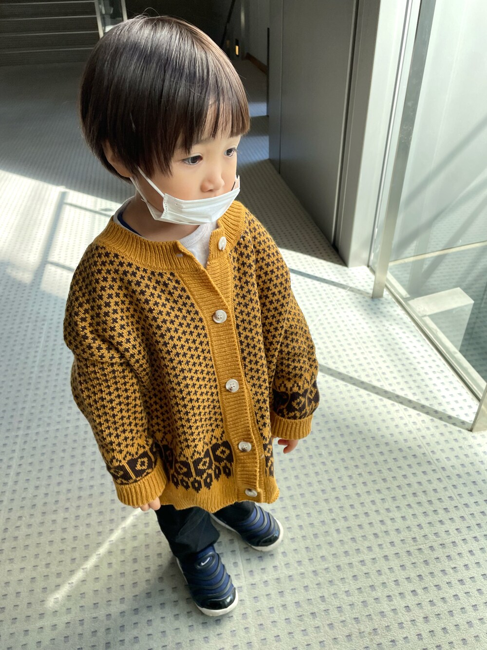 イエロー系のカーディガン/ボレロ、グレー系のTシャツ/カットソー、ブラック系のパンツを着用したキッズの冬コーディネートの2枚目の写真