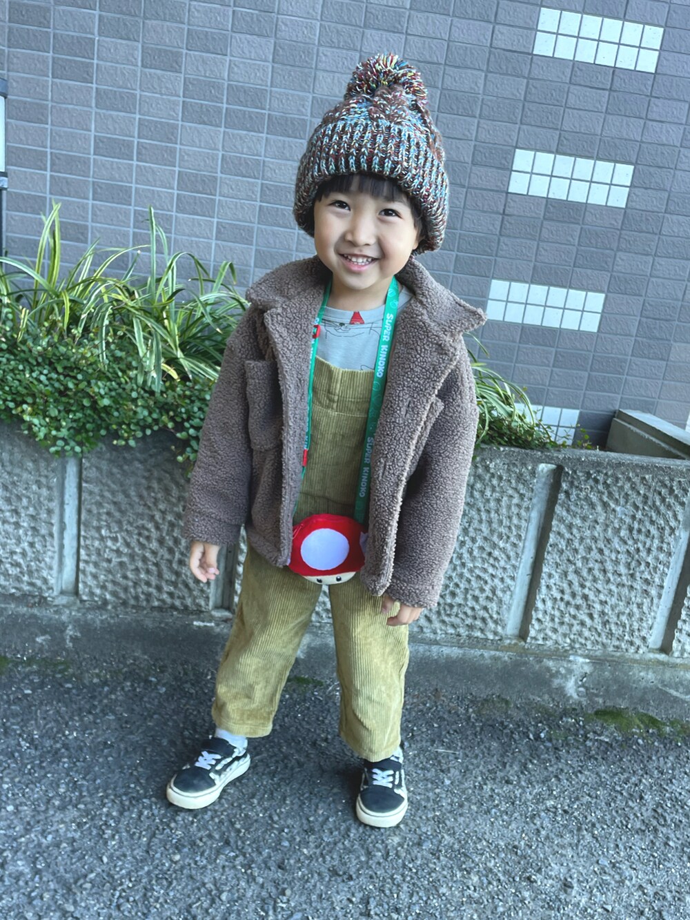 グレー系のTシャツ/カットソー、ベージュ系のサロペット/オーバーオール、ブラック系のスニーカーを着用したキッズの冬コーディネートの2枚目の写真