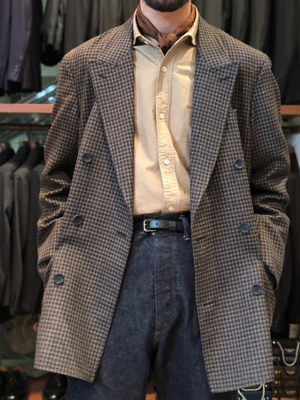 ブルー系のデニムパンツ、ホワイト系のスニーカー、ブラウン系のテーラードジャケットを着用したメンズの秋コーディネートの2枚目の写真