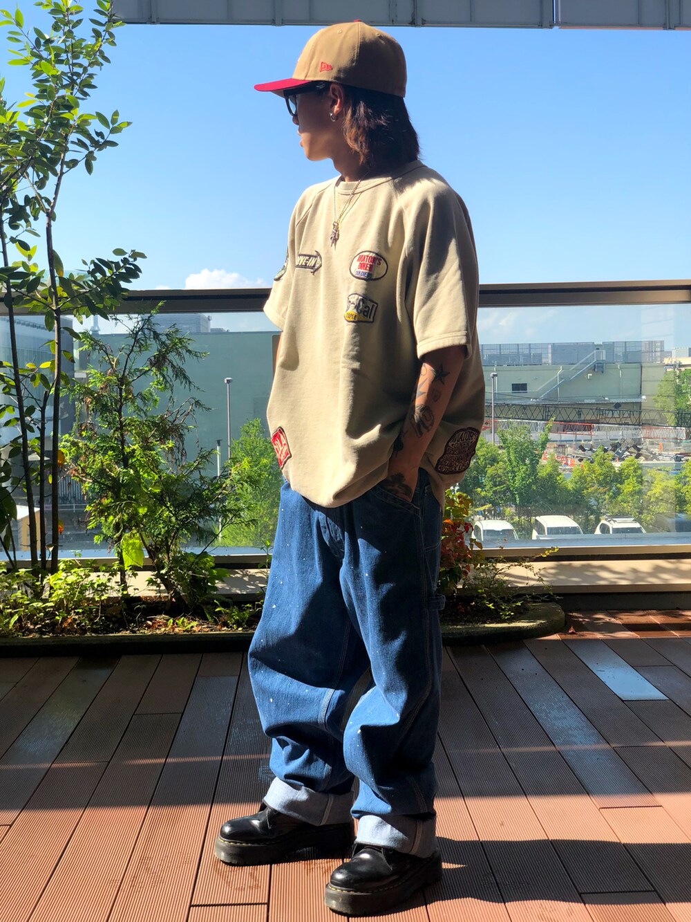 ベージュ系のTシャツ/カットソー、ブルー系のデニムパンツ、ブラウン系のキャップを着用したメンズの夏コーディネートの2枚目の写真