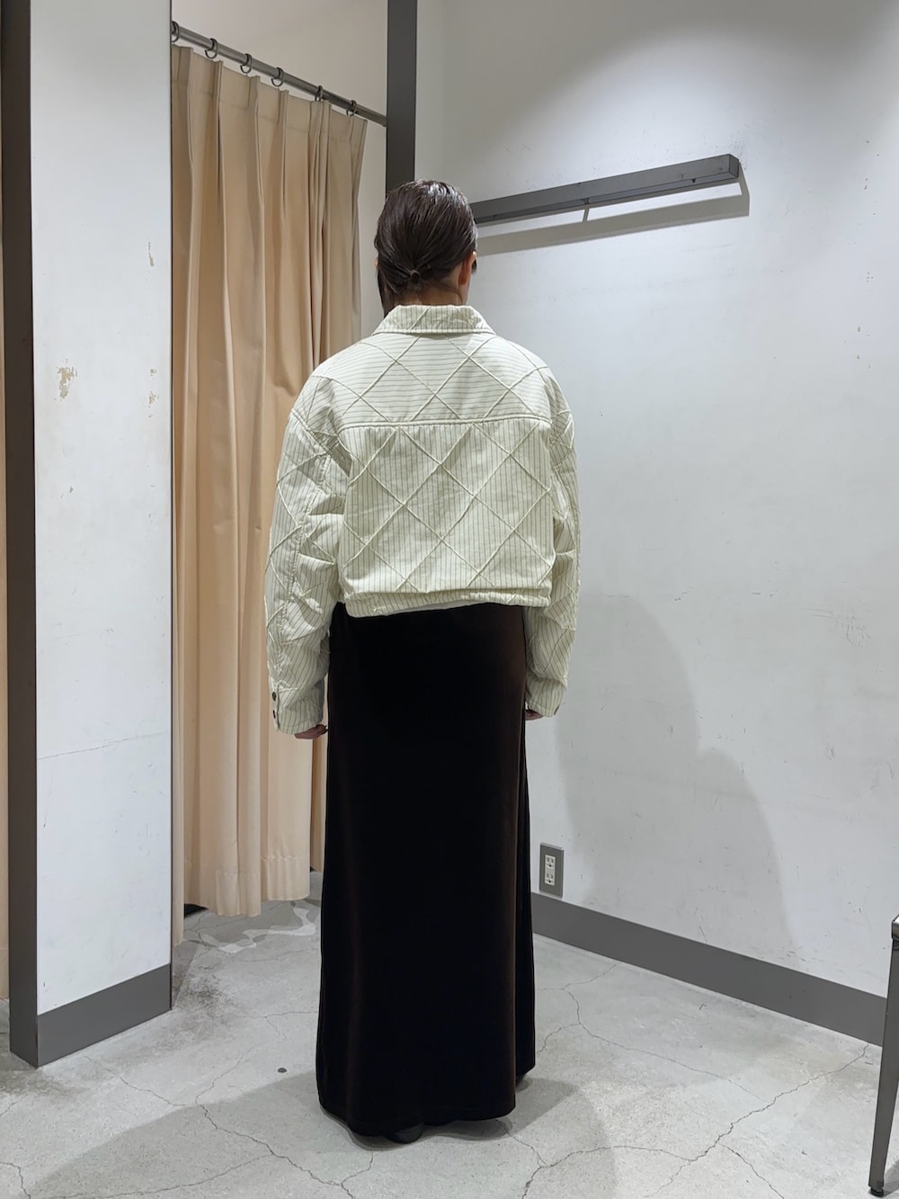 ブラウン系のスカート、ホワイト系のダウンジャケット/コートを着用したレディースの秋コーディネートの2枚目の写真