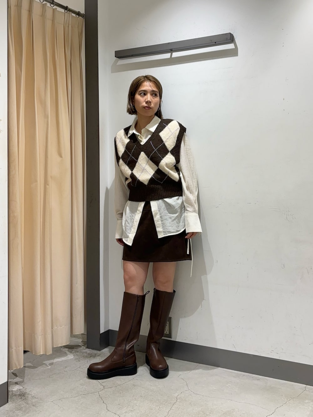 ブラウン系のベスト、ブラウン系のスカート、ホワイト系のシャツ/ブラウスを着用したレディースの秋コーディネートの2枚目の写真