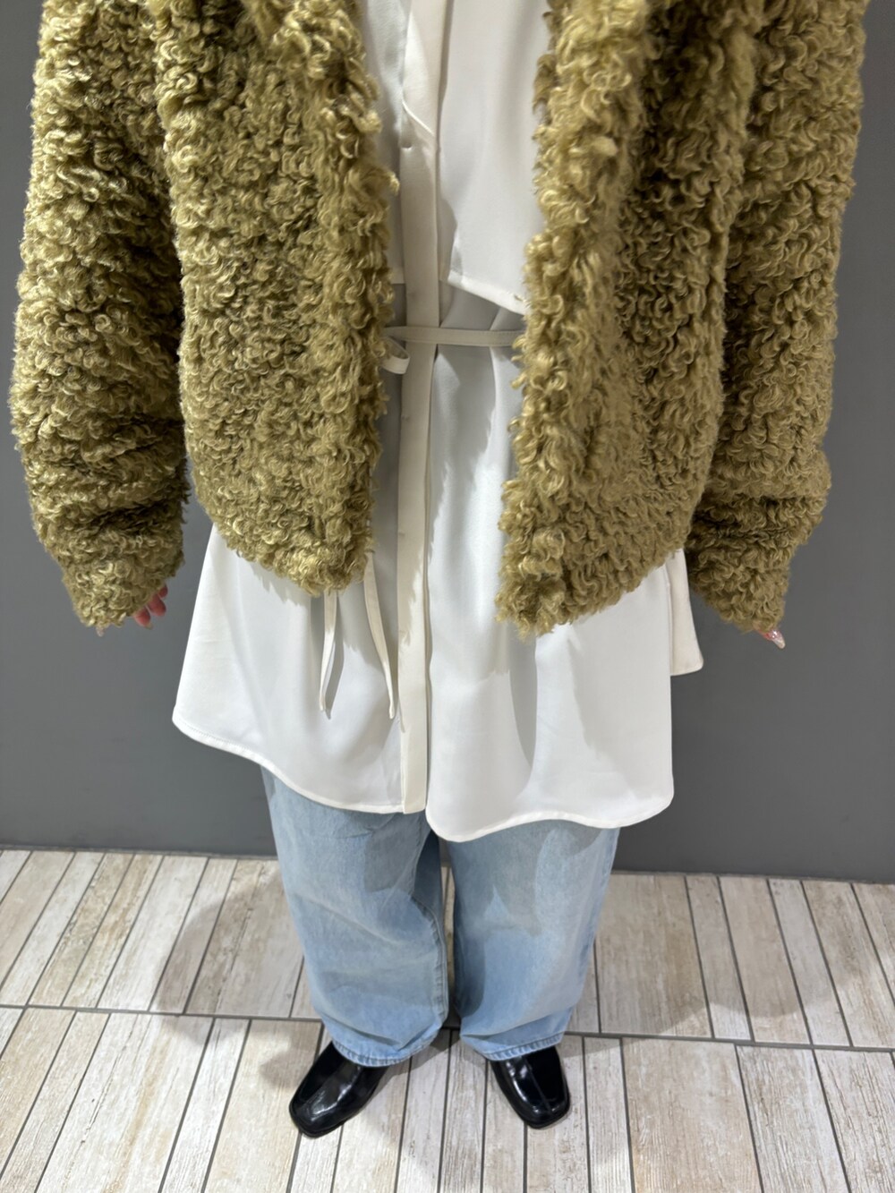 ブルー系のデニムパンツ、グリーン系のその他アウター、ホワイト系のワンピースを着用したレディースの冬コーディネートの3枚目の写真