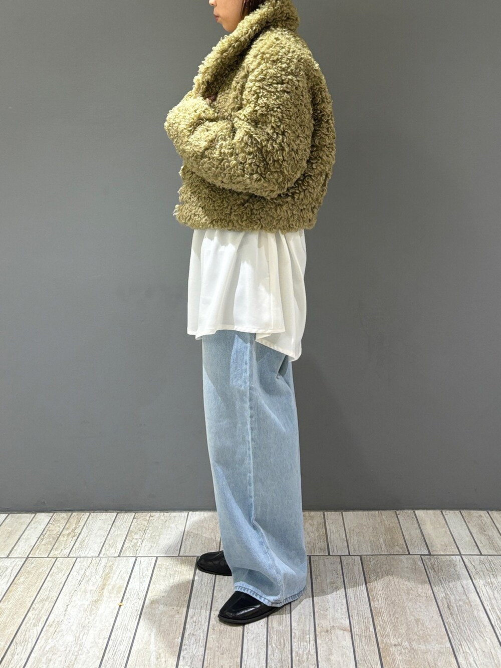 ブルー系のデニムパンツ、グリーン系のその他アウター、ホワイト系のワンピースを着用したレディースの冬コーディネートの2枚目の写真