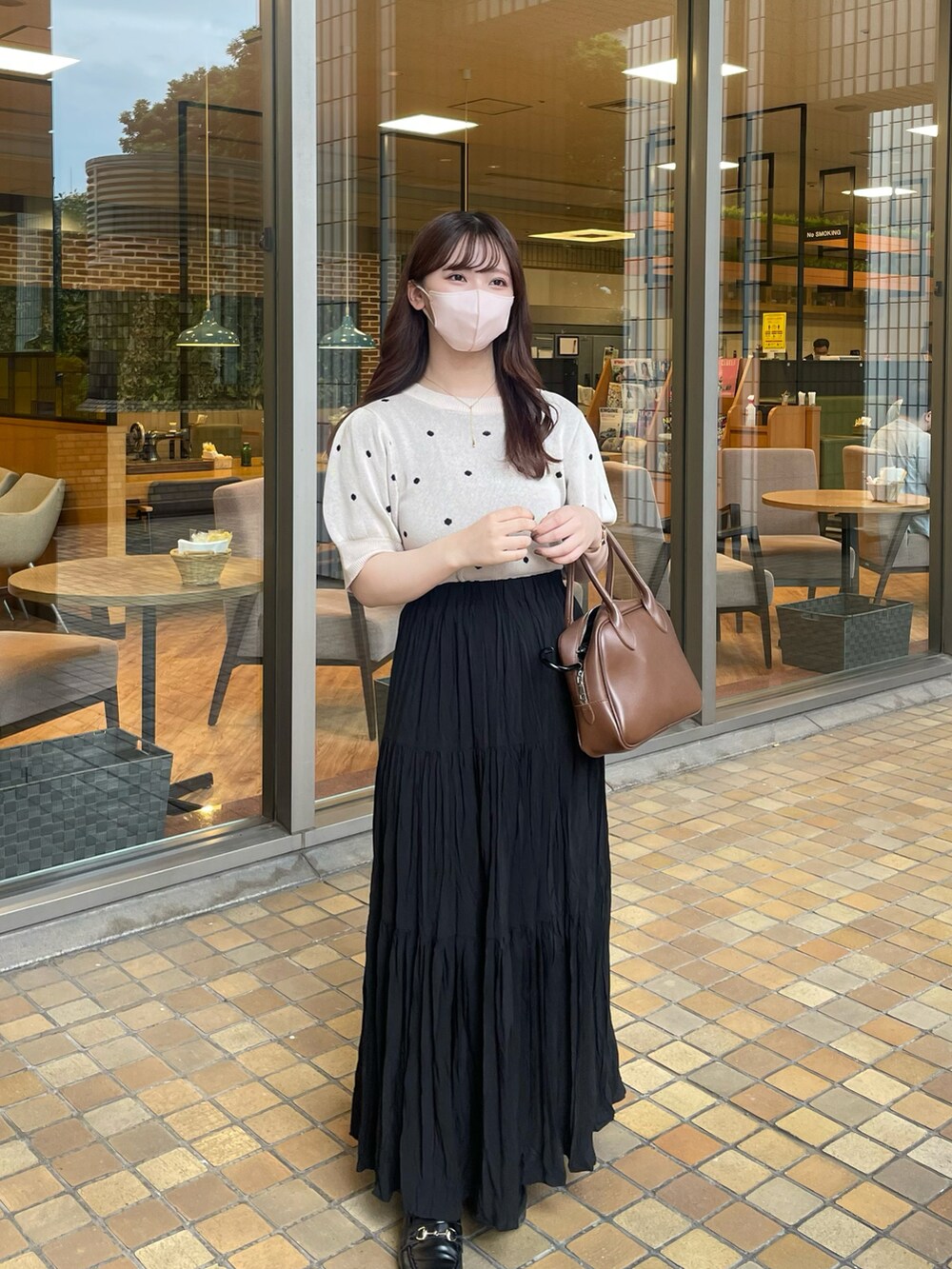 ベージュ系のニット/セーター、ブラック系のスカート、ブラック系のローファーを着用したレディースの夏コーディネートの2枚目の写真