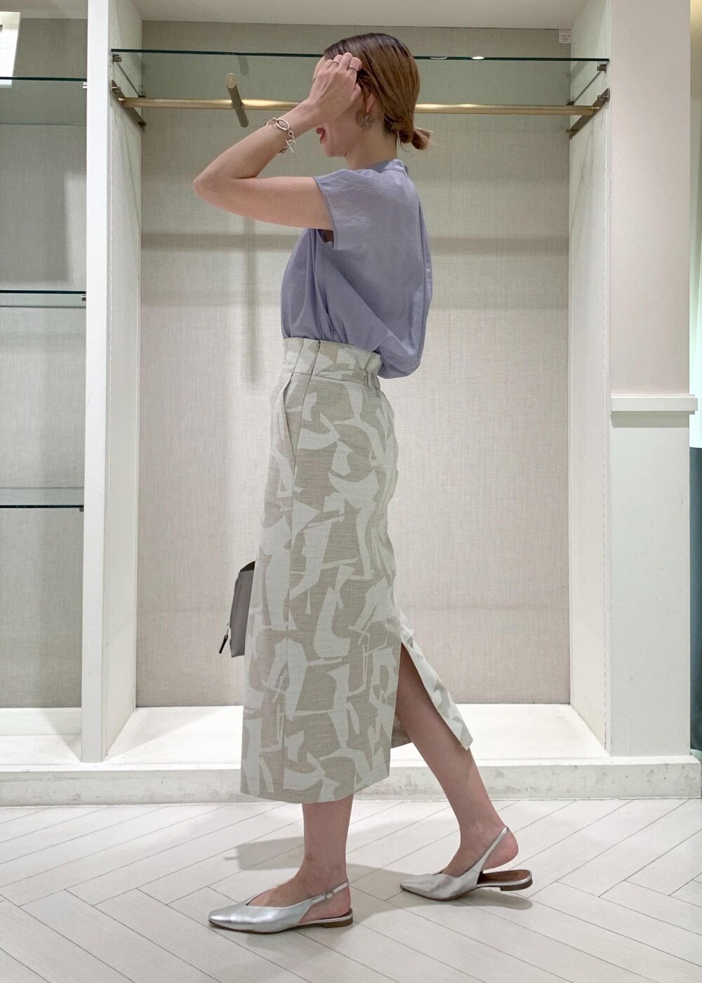 グレー系のハンドバッグ、シルバー系のパンプス、ベージュ系のスカートを着用したレディースの夏コーディネートの2枚目の写真