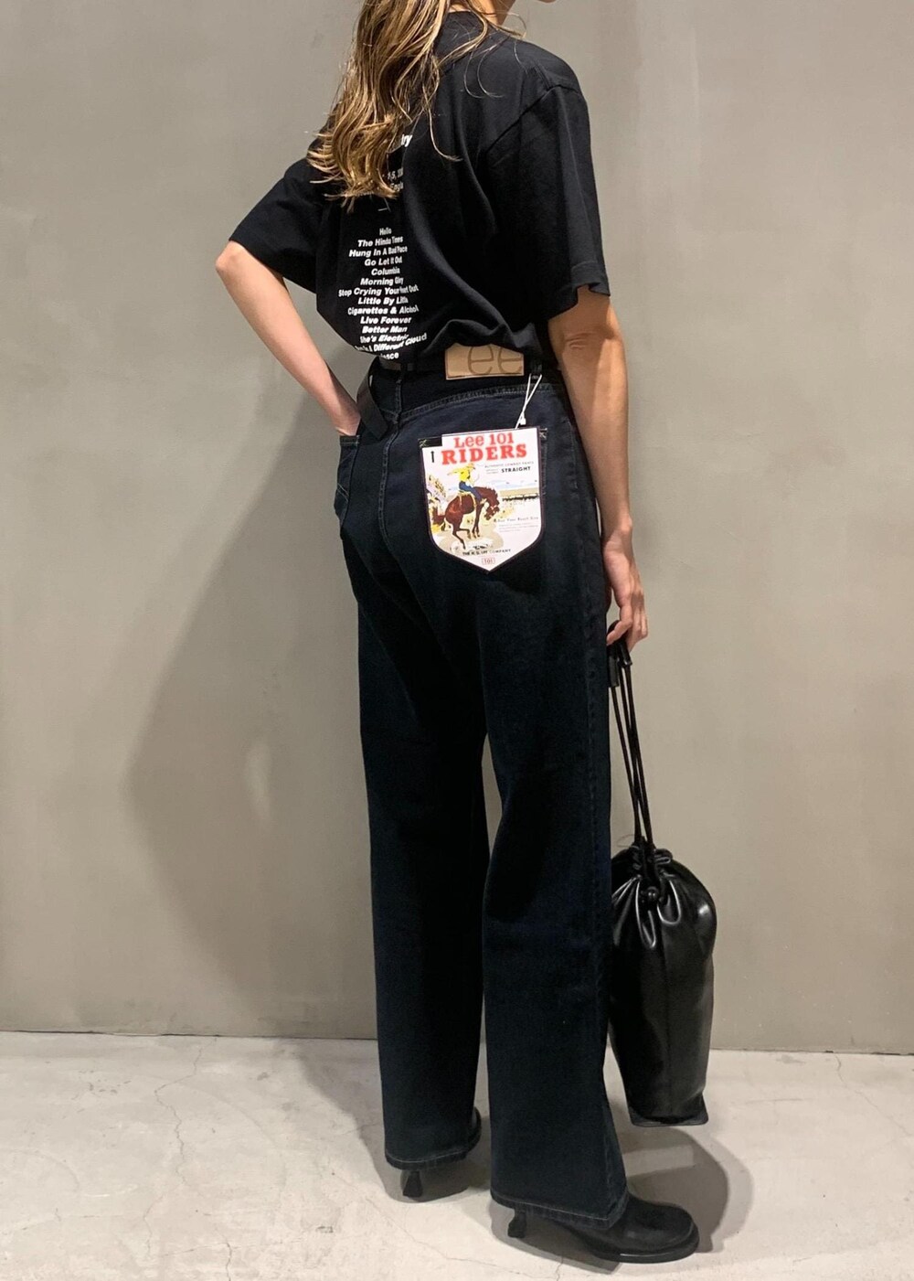 ブラック系のサンダル、ブラック系のショルダーバッグ、ブラック系のデニムパンツを着用したレディースの秋コーディネートの4枚目の写真