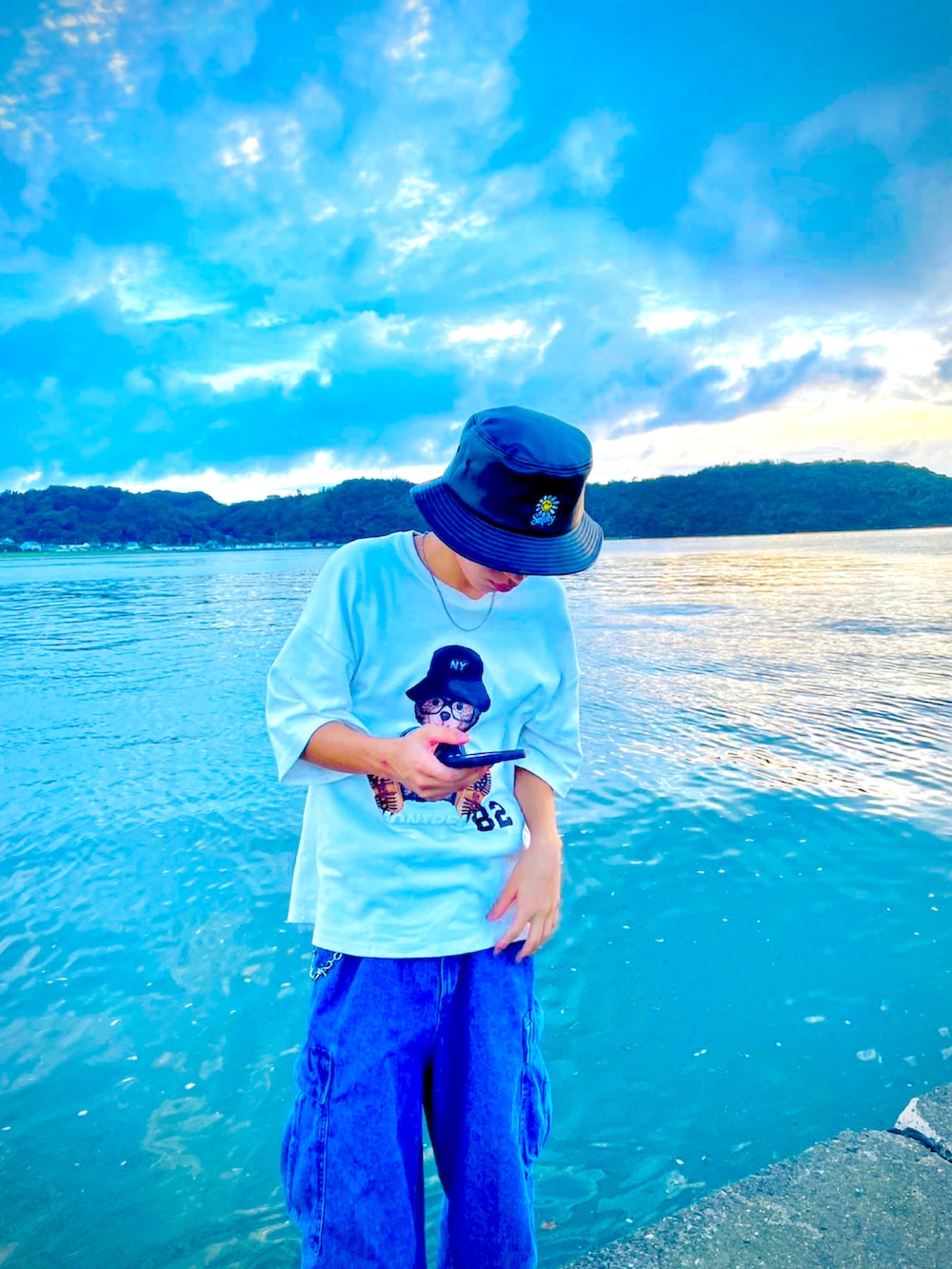 ブルー系のカーゴパンツ、ホワイト系のスニーカー、ブラック系のハットを着用したメンズの春コーディネートの2枚目の写真