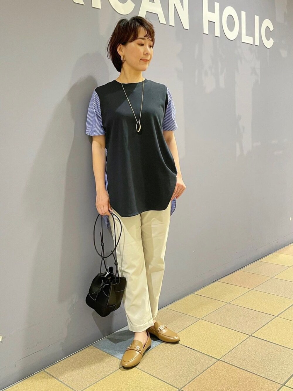 イエロー系のローファー、グレー系のその他パンツ、ブラック系のショルダーバッグを着用したレディースの夏コーディネートの5枚目の写真