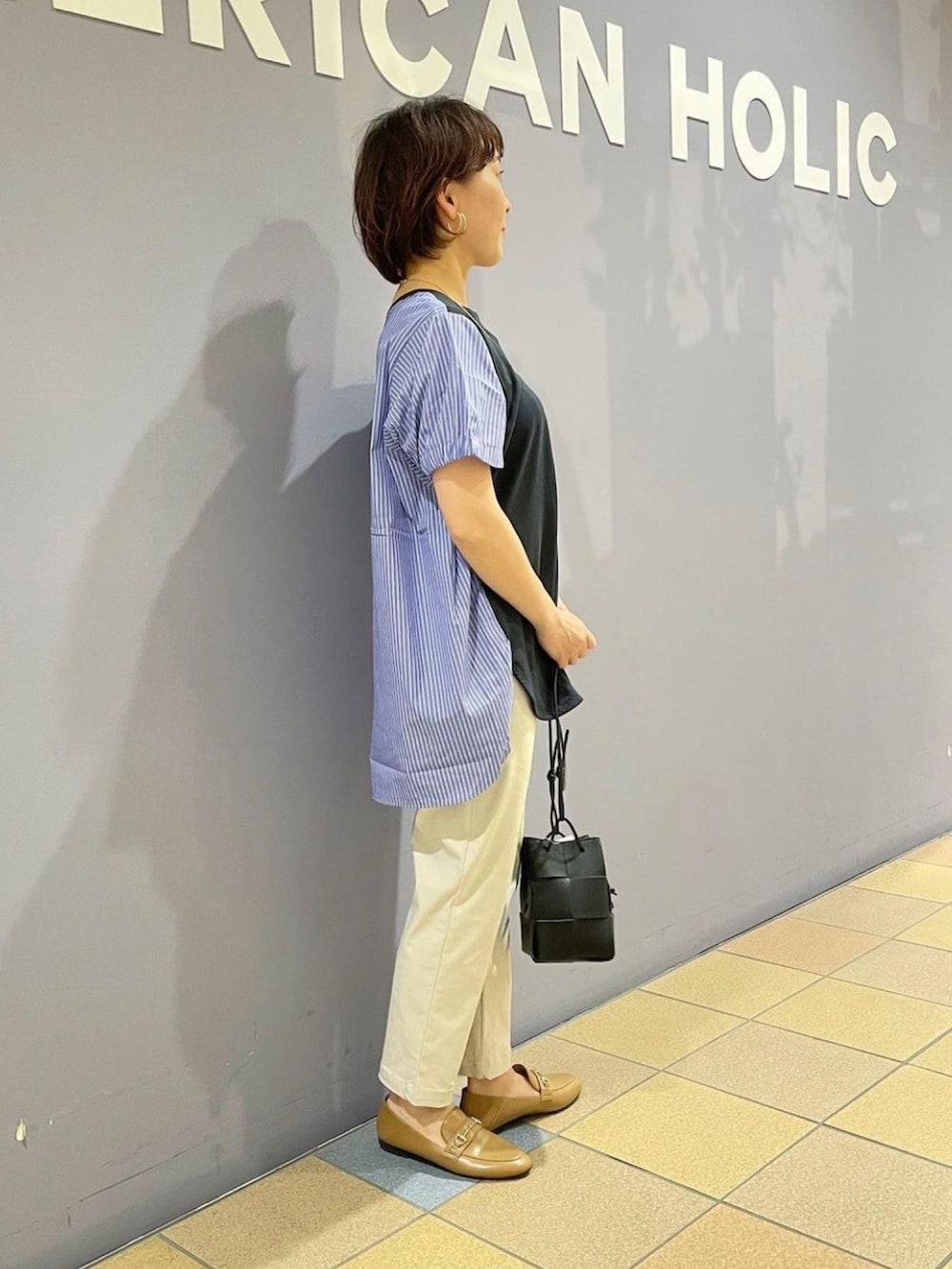 イエロー系のローファー、グレー系のその他パンツ、ブラック系のショルダーバッグを着用したレディースの夏コーディネートの3枚目の写真