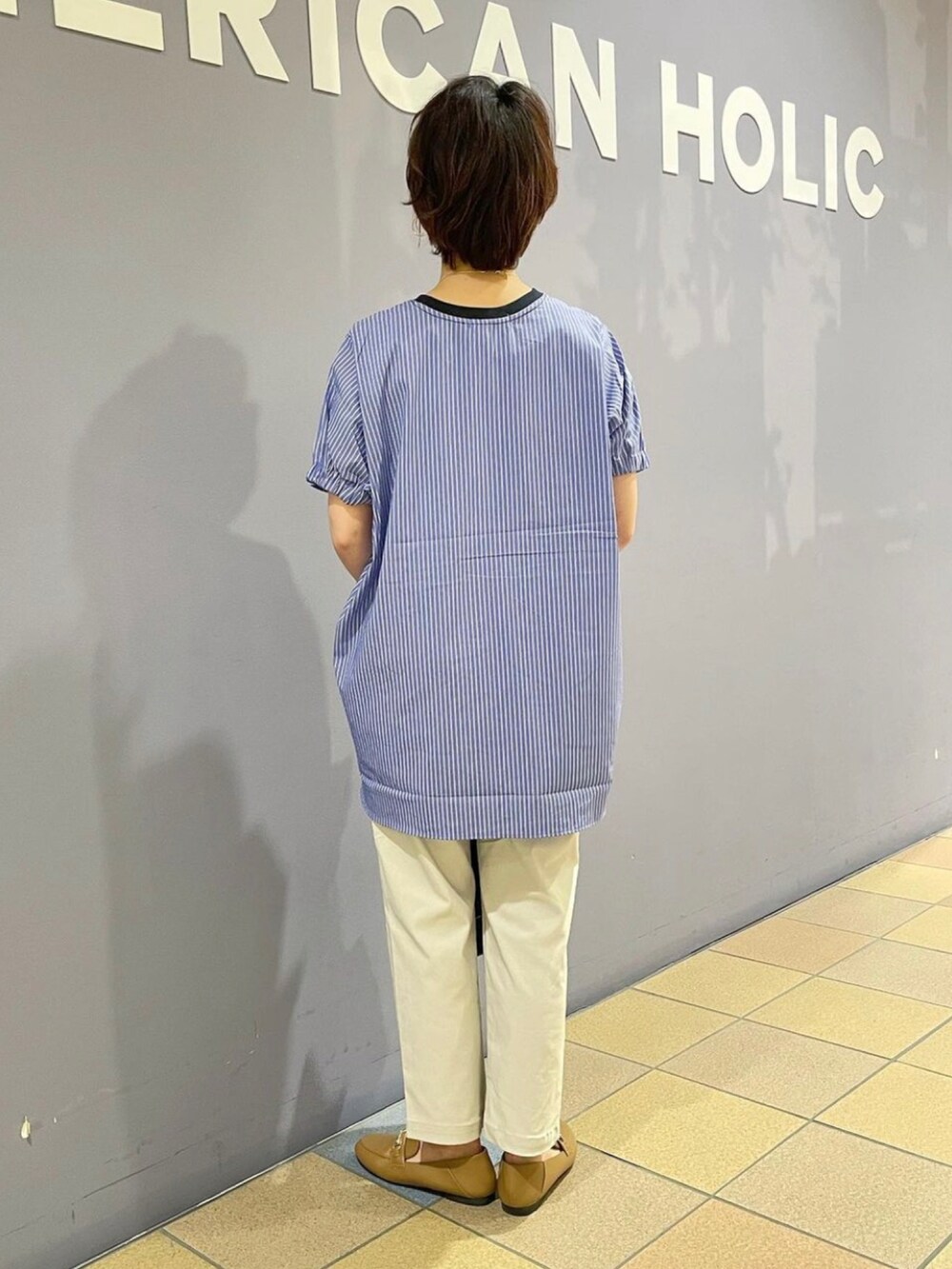 イエロー系のローファー、グレー系のその他パンツ、ブラック系のショルダーバッグを着用したレディースの夏コーディネートの4枚目の写真