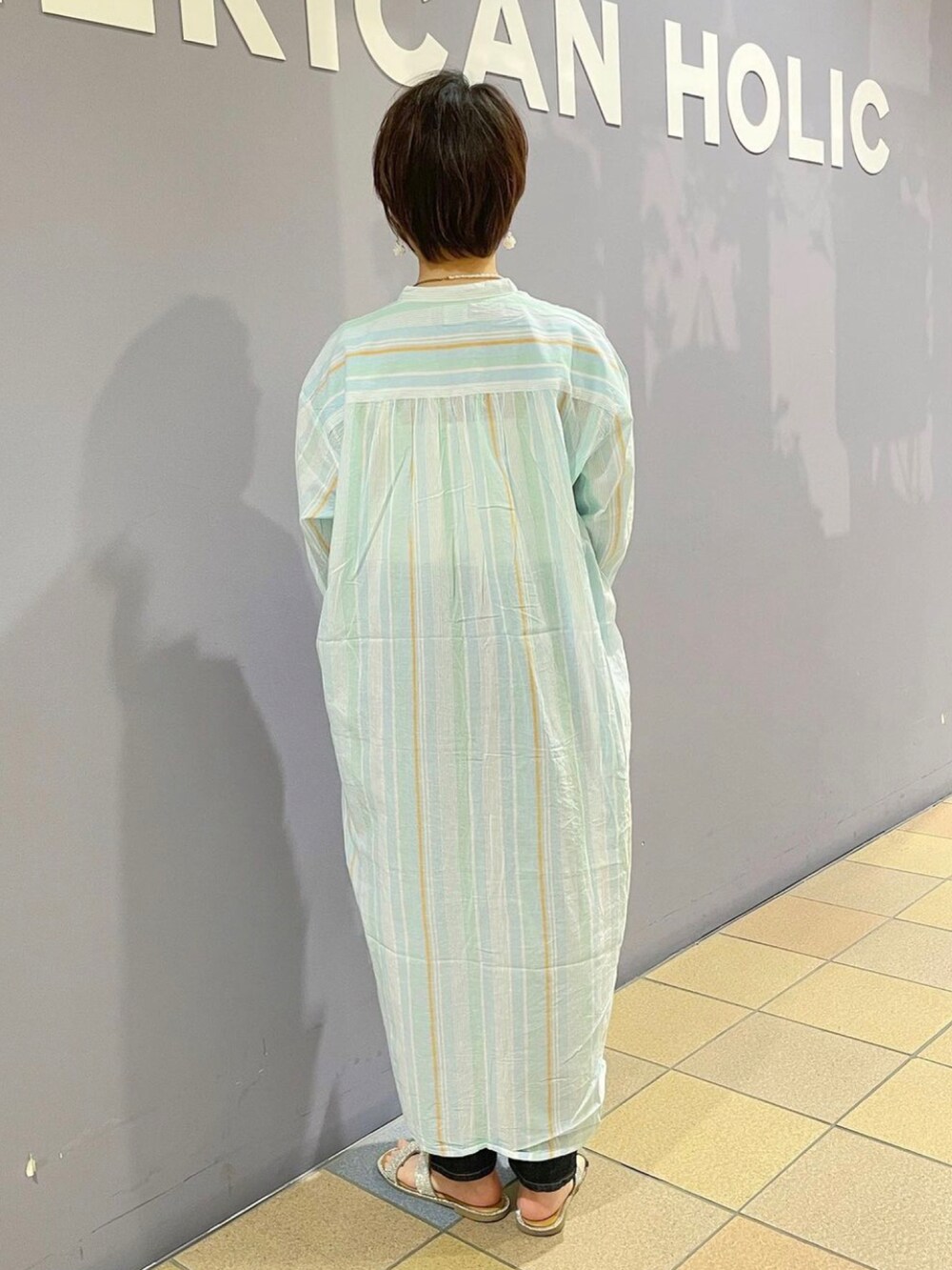 ホワイト系のショルダーバッグ、ブルー系のデニムパンツ、ブルー系のワンピースを着用したレディースの春コーディネートの4枚目の写真