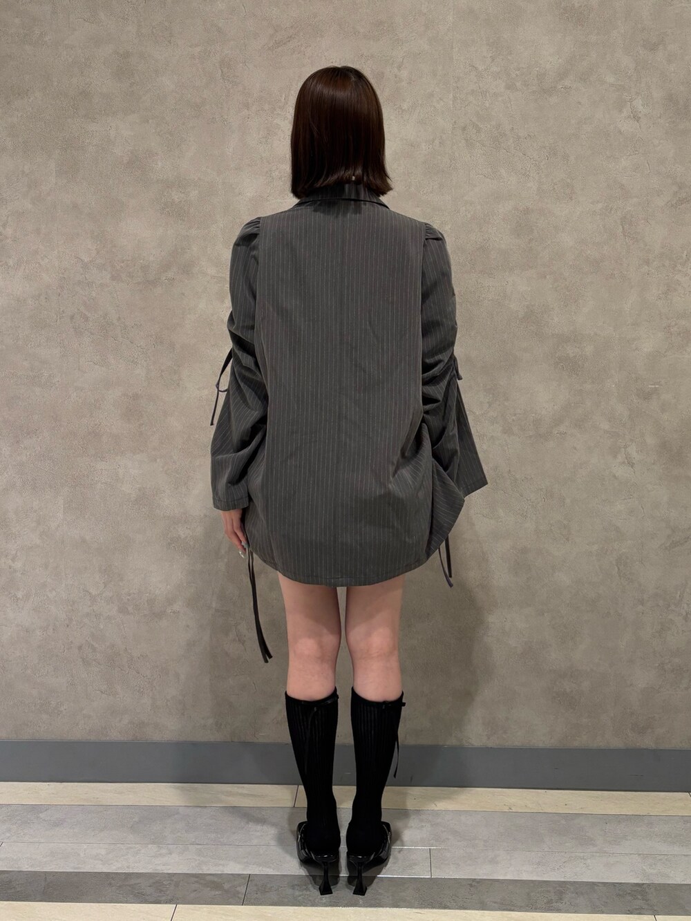 ホワイト系のワンピース、ブラック系のパンプス、グレー系のテーラードジャケットを着用したレディースの夏コーディネートの5枚目の写真