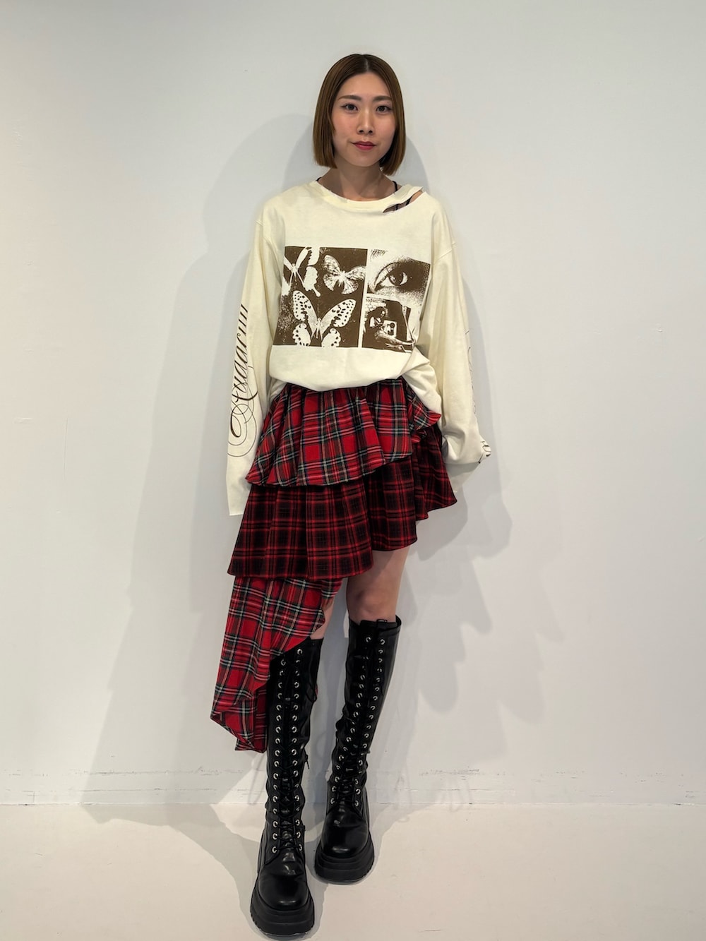 ブラック系のブーツ、ホワイト系のTシャツ/カットソー、レッド系のスカートを着用したレディースの冬コーディネートの2枚目の写真