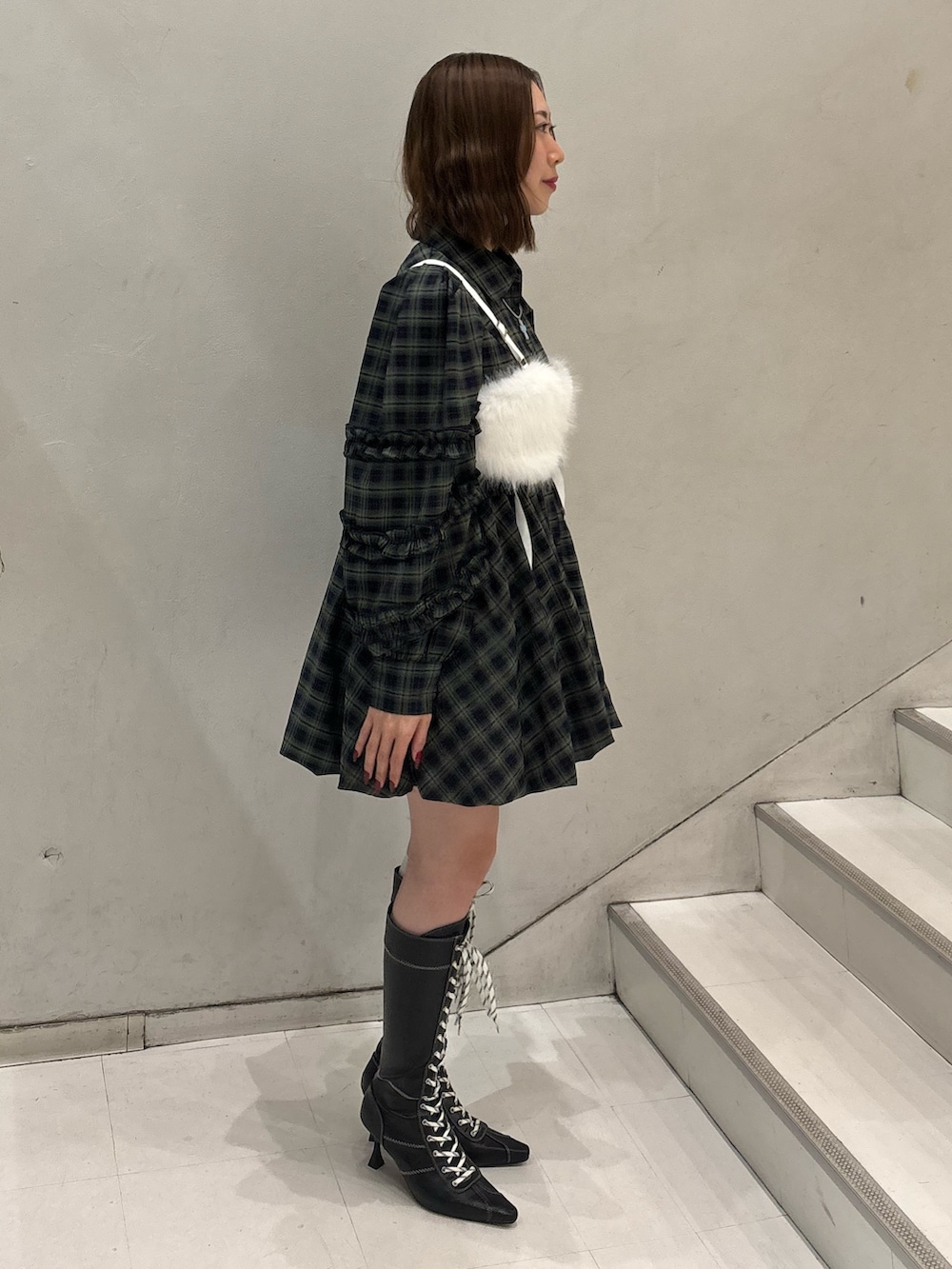 グリーン系のワンピース、ブラック系のブーツ、ホワイト系のベルトを着用したレディースの冬コーディネートの3枚目の写真