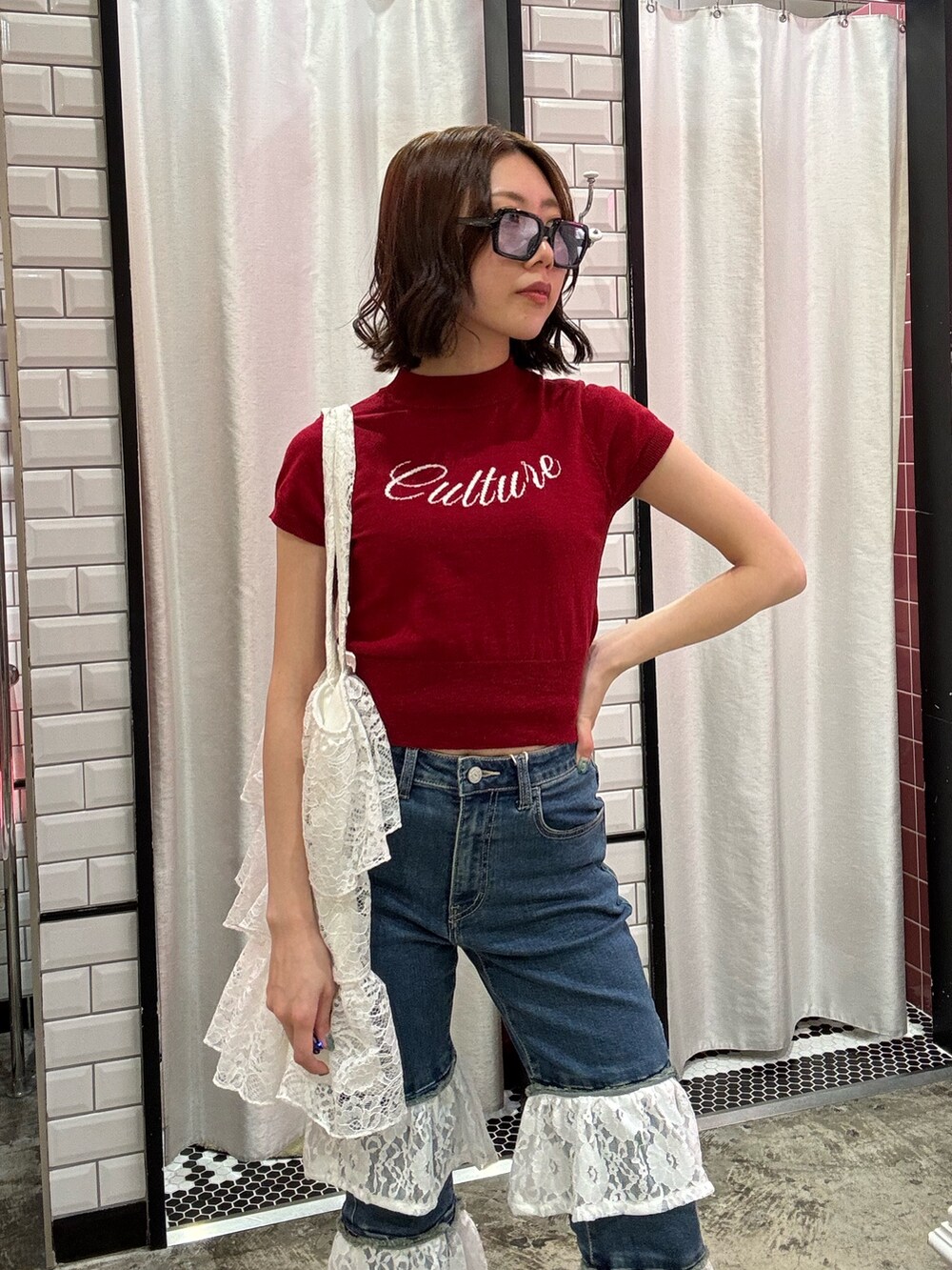 ブルー系のデニムパンツ、ホワイト系のトートバッグ、レッド系のニット/セーターを着用したレディースの春コーディネートの6枚目の写真