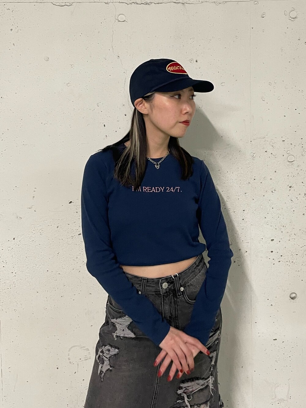 ブラック系のデニムスカート、ブラック系のTシャツ/カットソー、ブルー系のキャップを着用したレディースの冬コーディネートの6枚目の写真