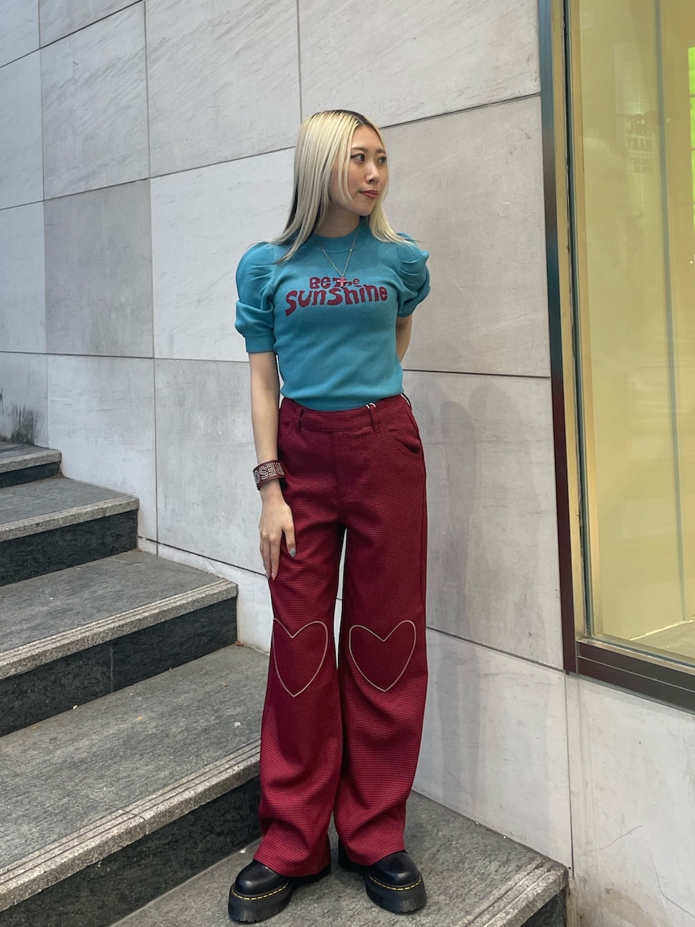 ブルー系のニット/セーター、レッド系のその他パンツ、レッド系のブレスレットを着用したレディースの夏コーディネートの2枚目の写真