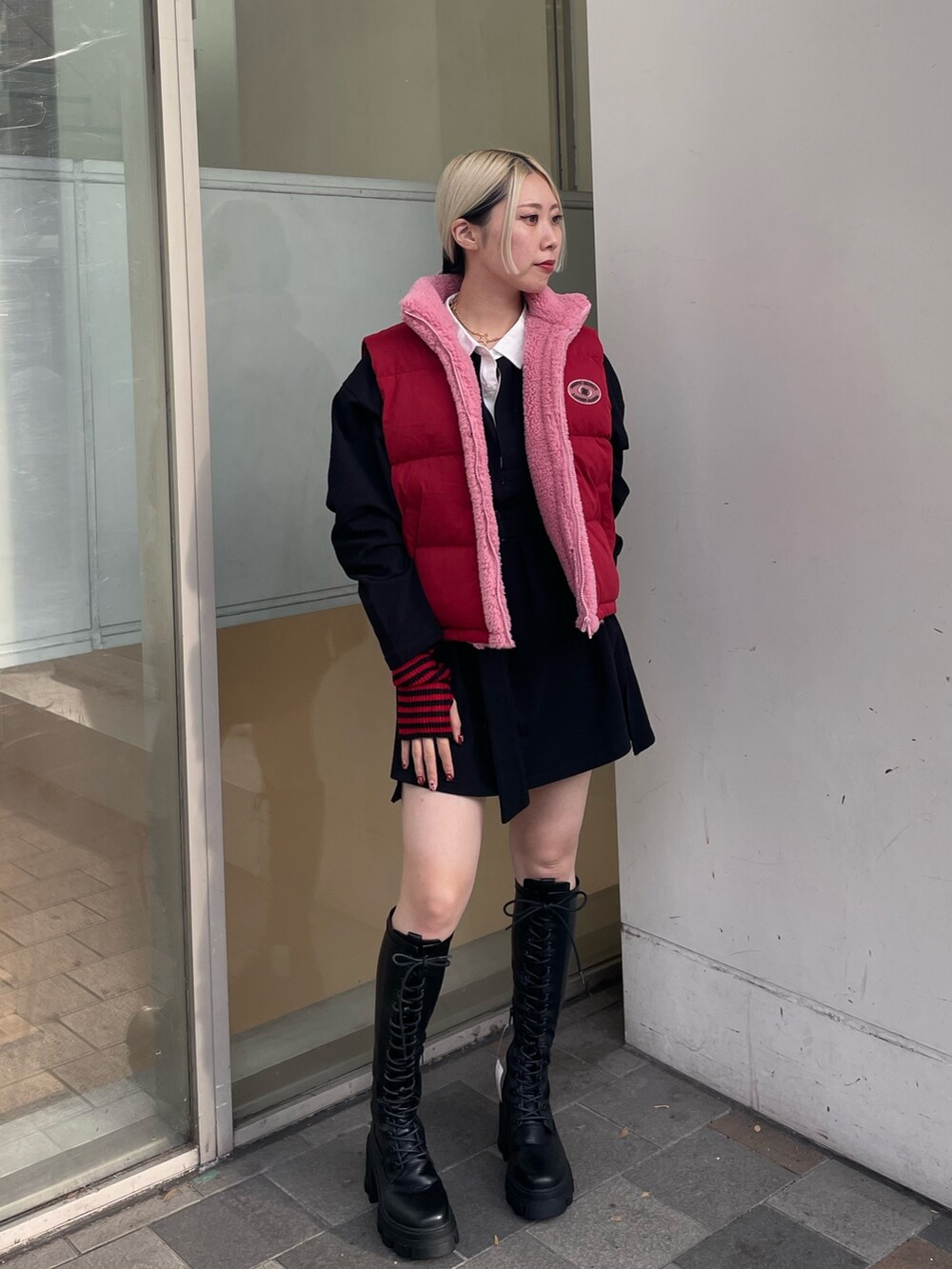 ブラック系のシャツワンピース、レッド系のダウンベスト、ブラック系のブーツを着用したレディースの秋コーディネートの3枚目の写真