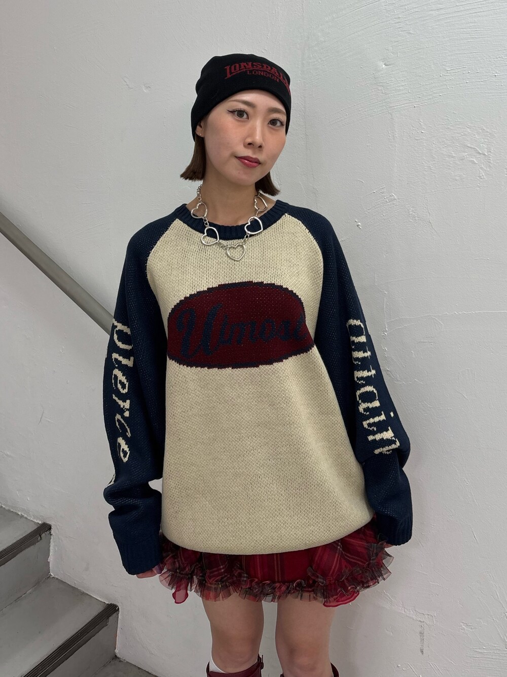 レッド系のブーツ、レッド系のスカート、ホワイト系のニット/セーターを着用したレディースの秋コーディネートの6枚目の写真