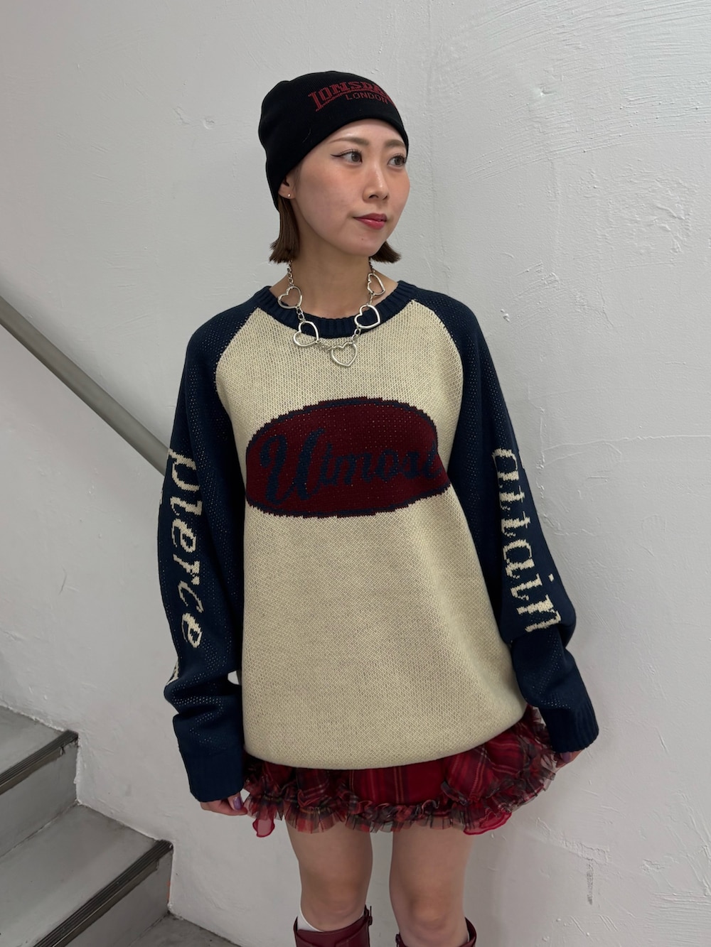 レッド系のブーツ、レッド系のスカート、ホワイト系のニット/セーターを着用したレディースの秋コーディネートの5枚目の写真