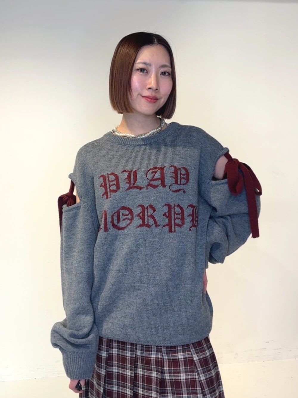 ブラック系のブーツ、レッド系のスカート、グレー系のニット/セーターを着用したレディースの秋コーディネートの4枚目の写真