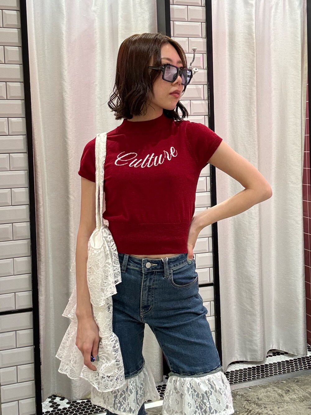 ブルー系のデニムパンツ、ホワイト系のトートバッグ、レッド系のニット/セーターを着用したレディースの春コーディネートの5枚目の写真