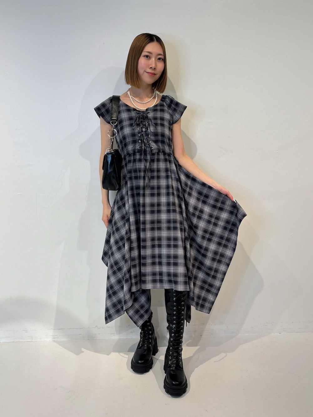 ブルー系のワンピース、ブラック系のブーツ、ブラック系のハンドバッグを着用したレディースの夏コーディネートの2枚目の写真