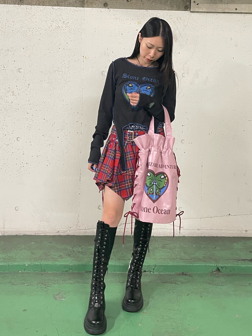 レッド系のスカート、ブラック系のブーツ、ブラック系のTシャツ/カットソーを着用したレディースの秋コーディネートの3枚目の写真