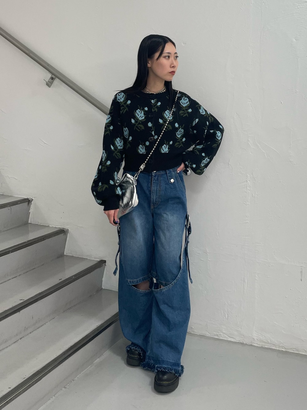 ブルー系のデニムパンツ、ブラック系のカーディガン/ボレロ、シルバー系のハンドバッグを着用したレディースの秋コーディネートの2枚目の写真