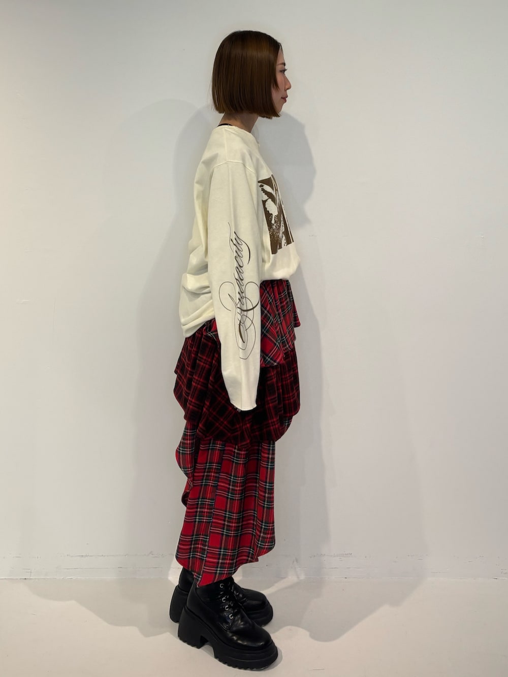 ブラック系のブーツ、ホワイト系のTシャツ/カットソー、レッド系のスカートを着用したレディースの冬コーディネートの3枚目の写真