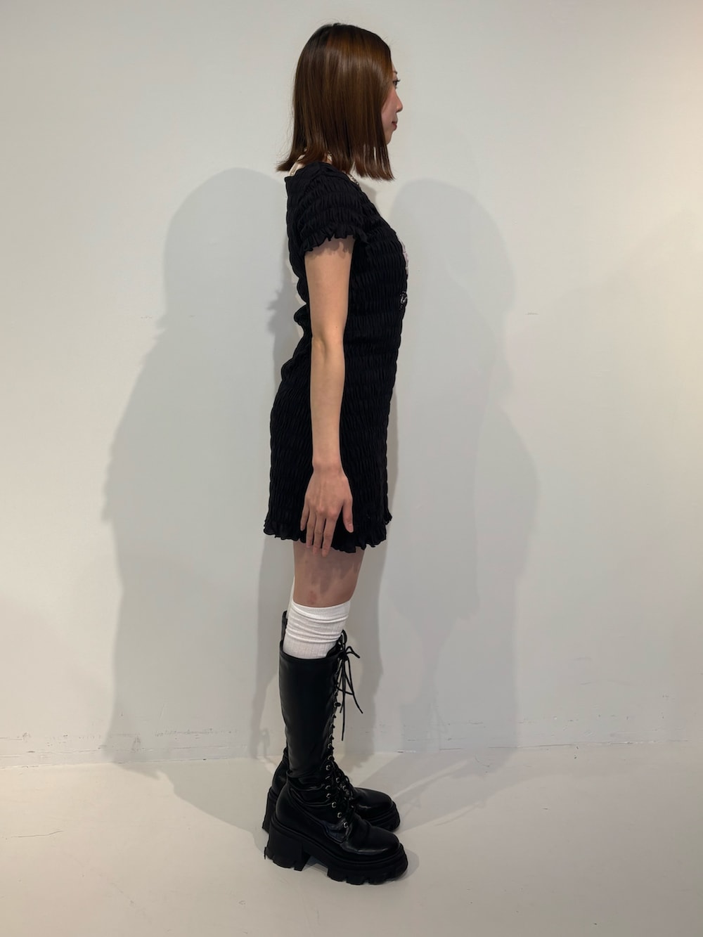 ブラック系のワンピース、ブラック系のブーツ、ホワイト系のキャミソールを着用したレディースの冬コーディネートの3枚目の写真