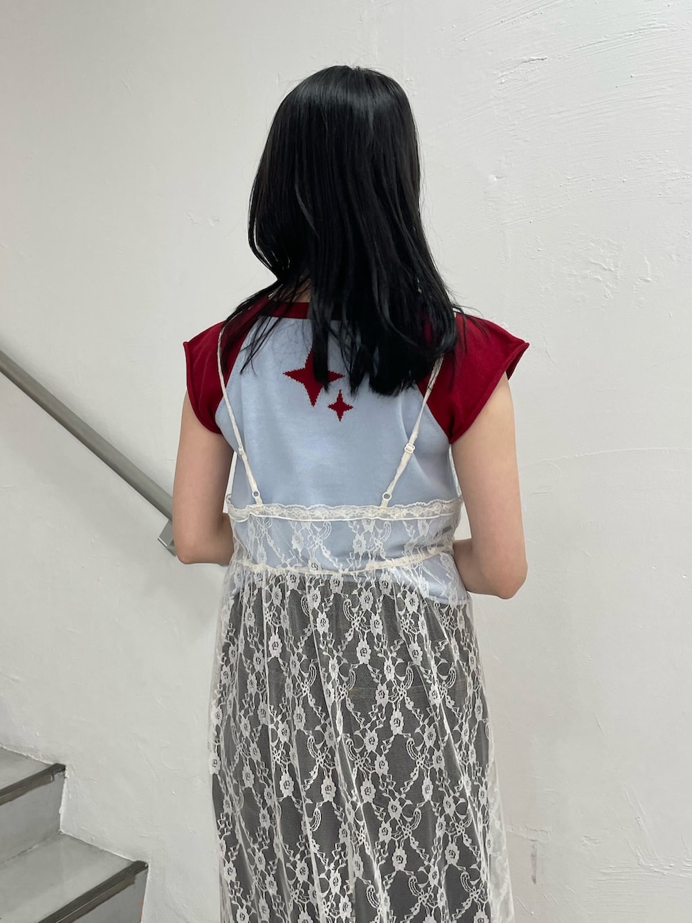 ブルー系のニット/セーター、ホワイト系のワンピース、ブラック系のデニムパンツを着用したレディースの春コーディネートの5枚目の写真