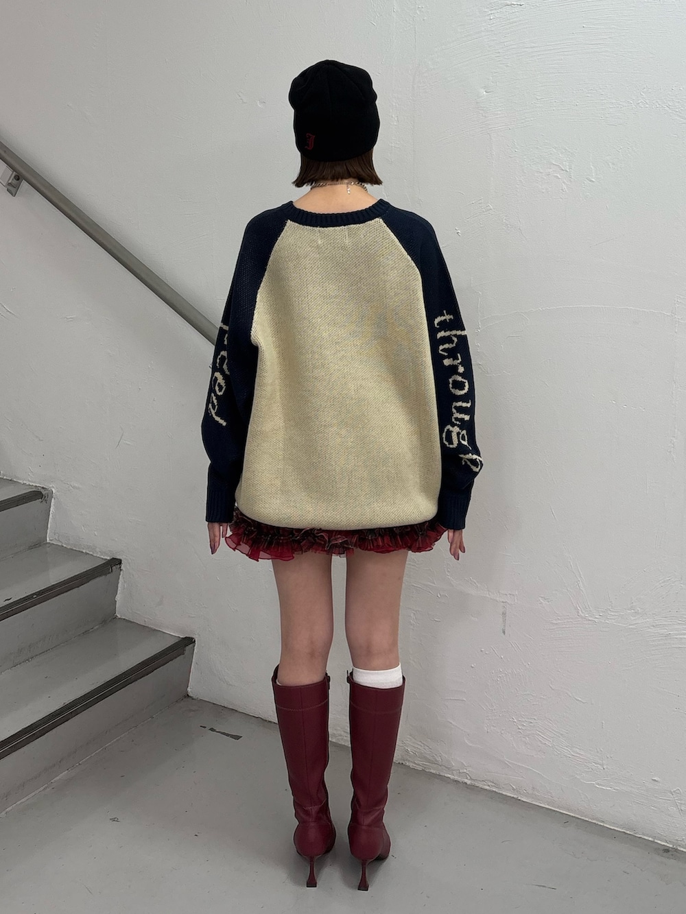 レッド系のブーツ、レッド系のスカート、ホワイト系のニット/セーターを着用したレディースの秋コーディネートの4枚目の写真