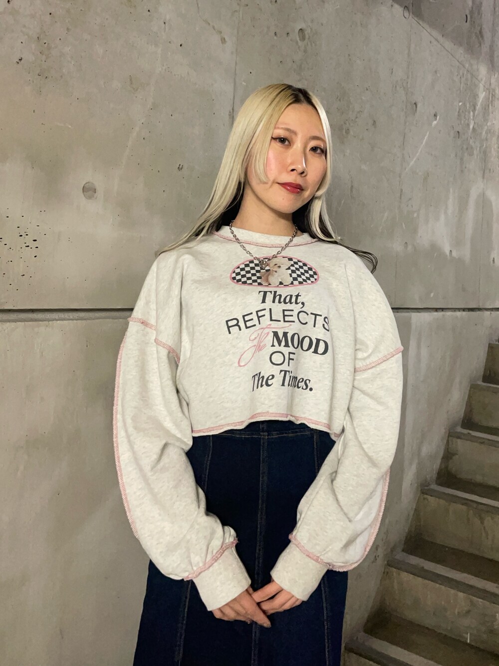 グレー系のスウェット、ブルー系のジャンパースカート、ブラック系のブーツを着用したレディースの冬コーディネートの4枚目の写真