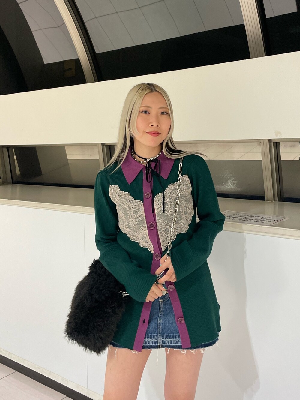 グリーン系のカーディガン/ボレロ、ブルー系のデニムパンツ、ブラック系のハンドバッグを着用したレディースの冬コーディネートの6枚目の写真