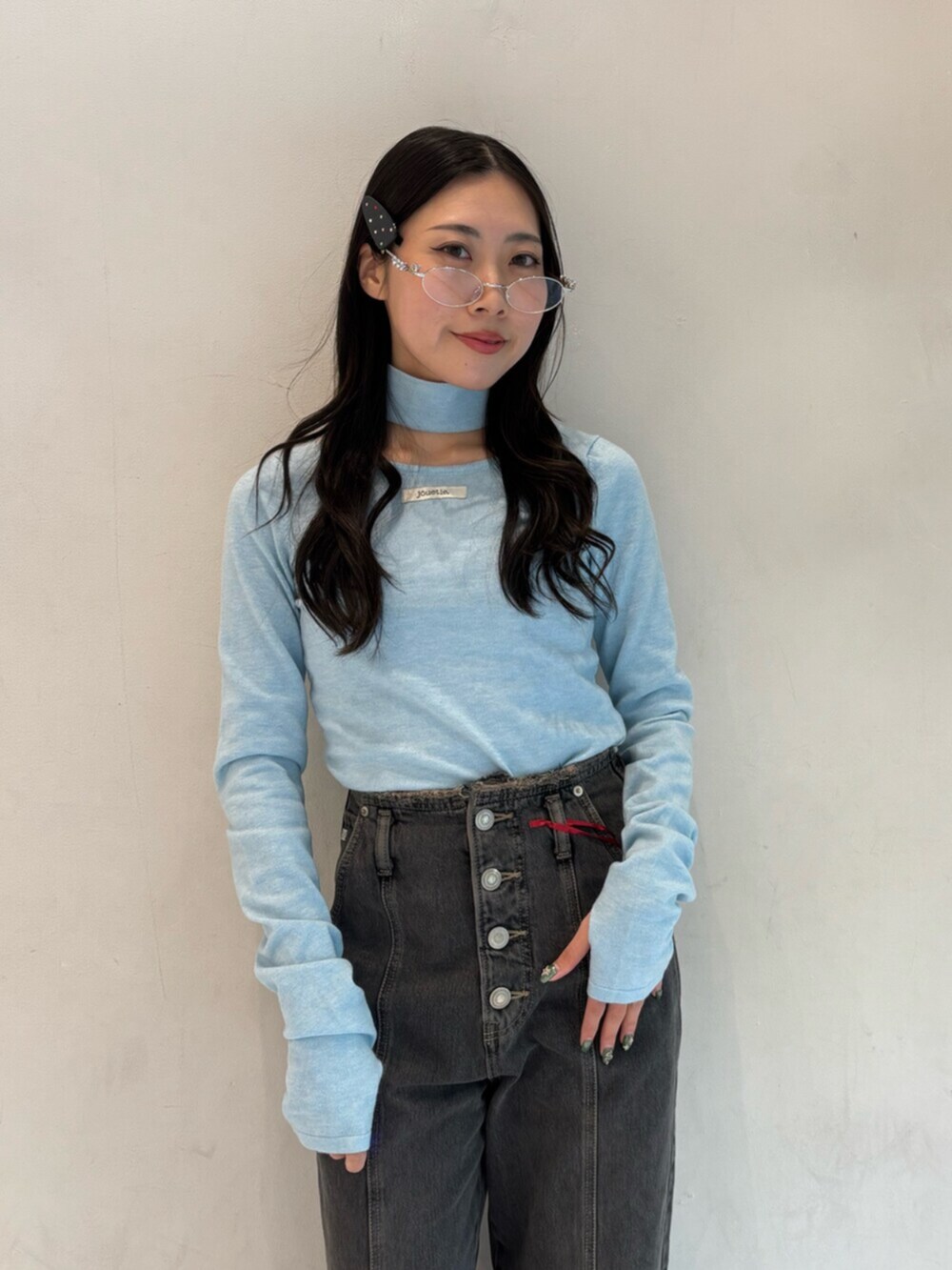 ブラック系のデニムパンツ、ブルー系のニット/セーター、シルバー系のメガネを着用したレディースの冬コーディネートの5枚目の写真