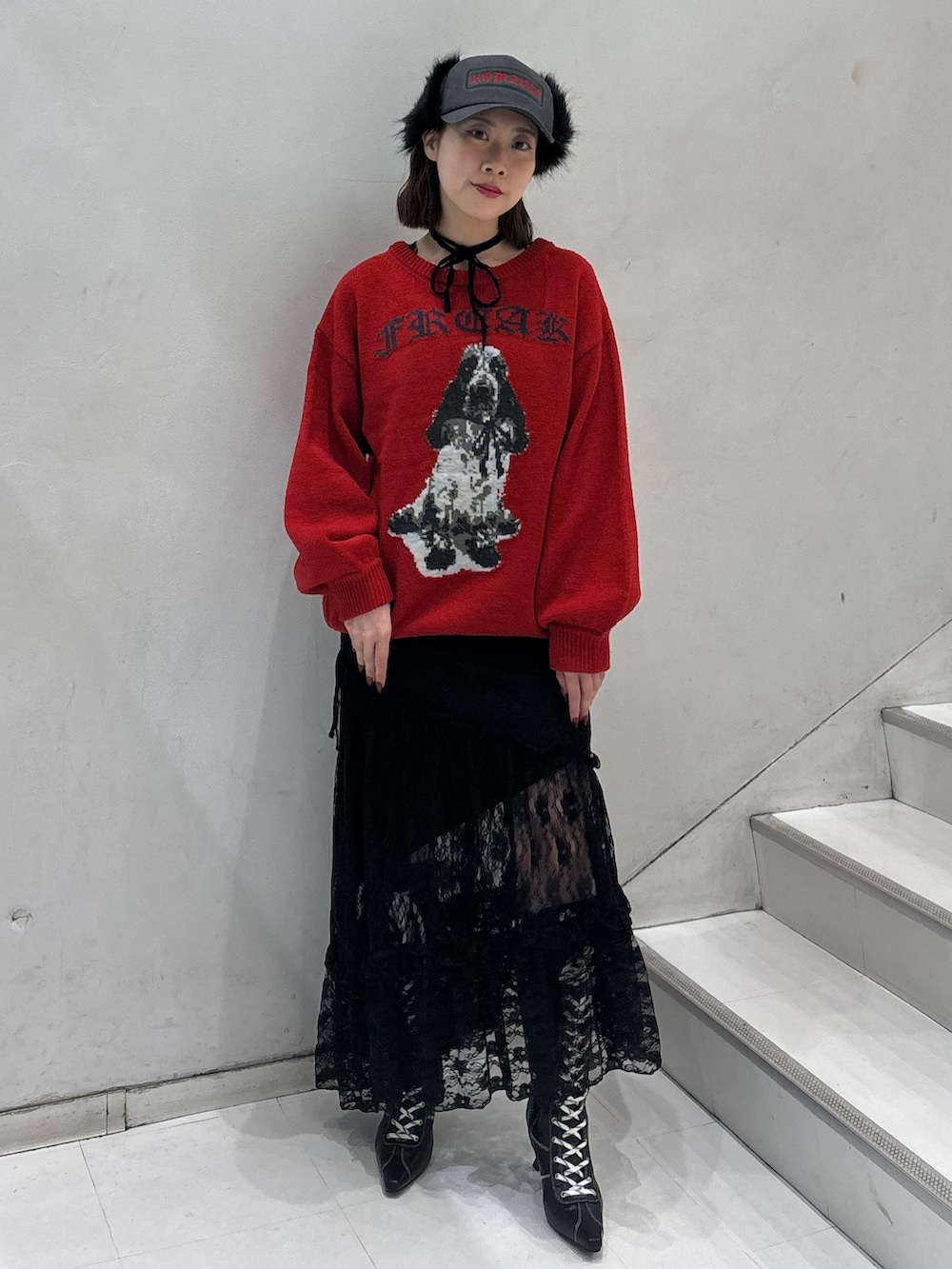 レッド系のニット/セーター、ブラック系のワンピース、ブラック系のブーツを着用したレディースの冬コーディネートの2枚目の写真