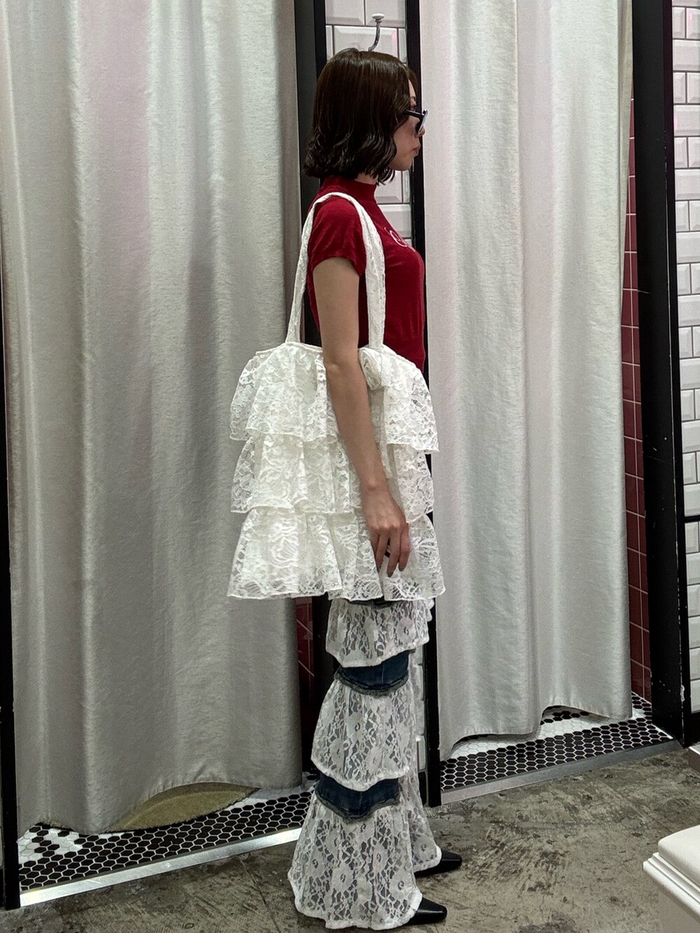 ブルー系のデニムパンツ、ホワイト系のトートバッグ、レッド系のニット/セーターを着用したレディースの春コーディネートの3枚目の写真