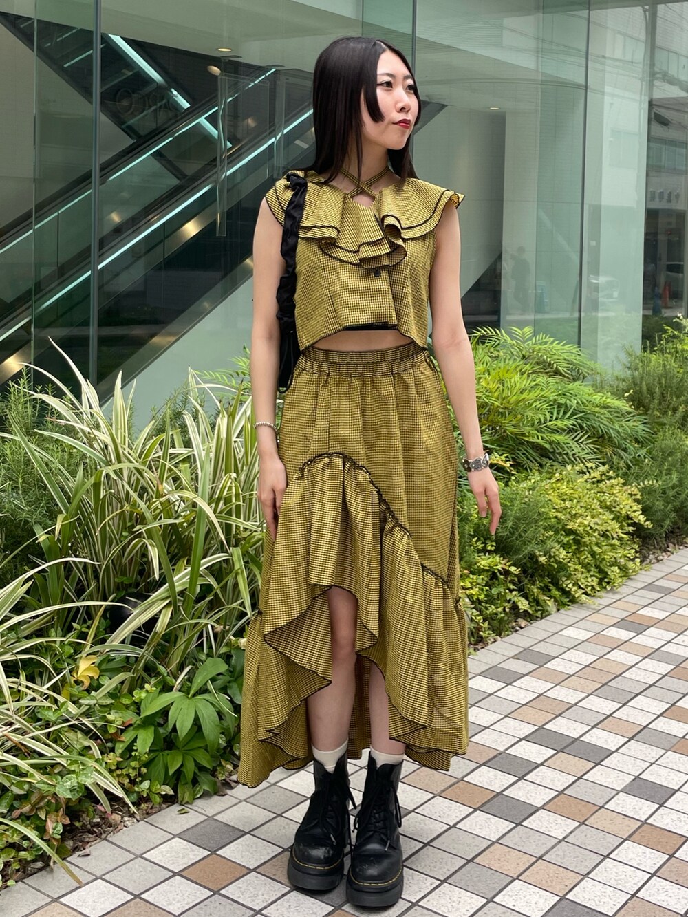 イエロー系のスカート、イエロー系のシャツ/ブラウス、ブラック系のショルダーバッグを着用したレディースの夏コーディネートの2枚目の写真