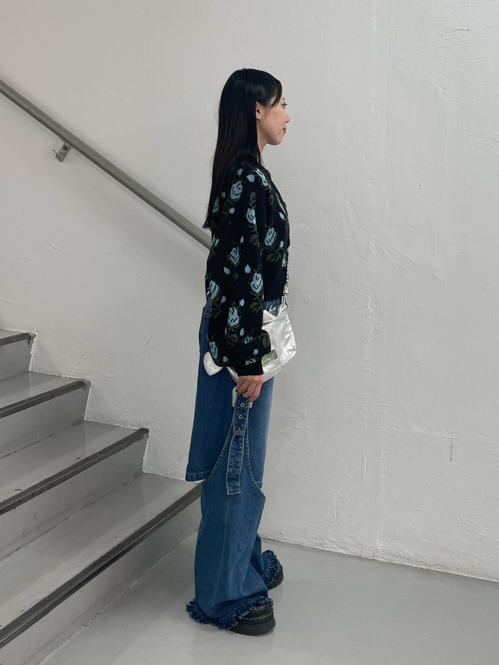 ブルー系のデニムパンツ、ブラック系のカーディガン/ボレロ、シルバー系のハンドバッグを着用したレディースの秋コーディネートの4枚目の写真
