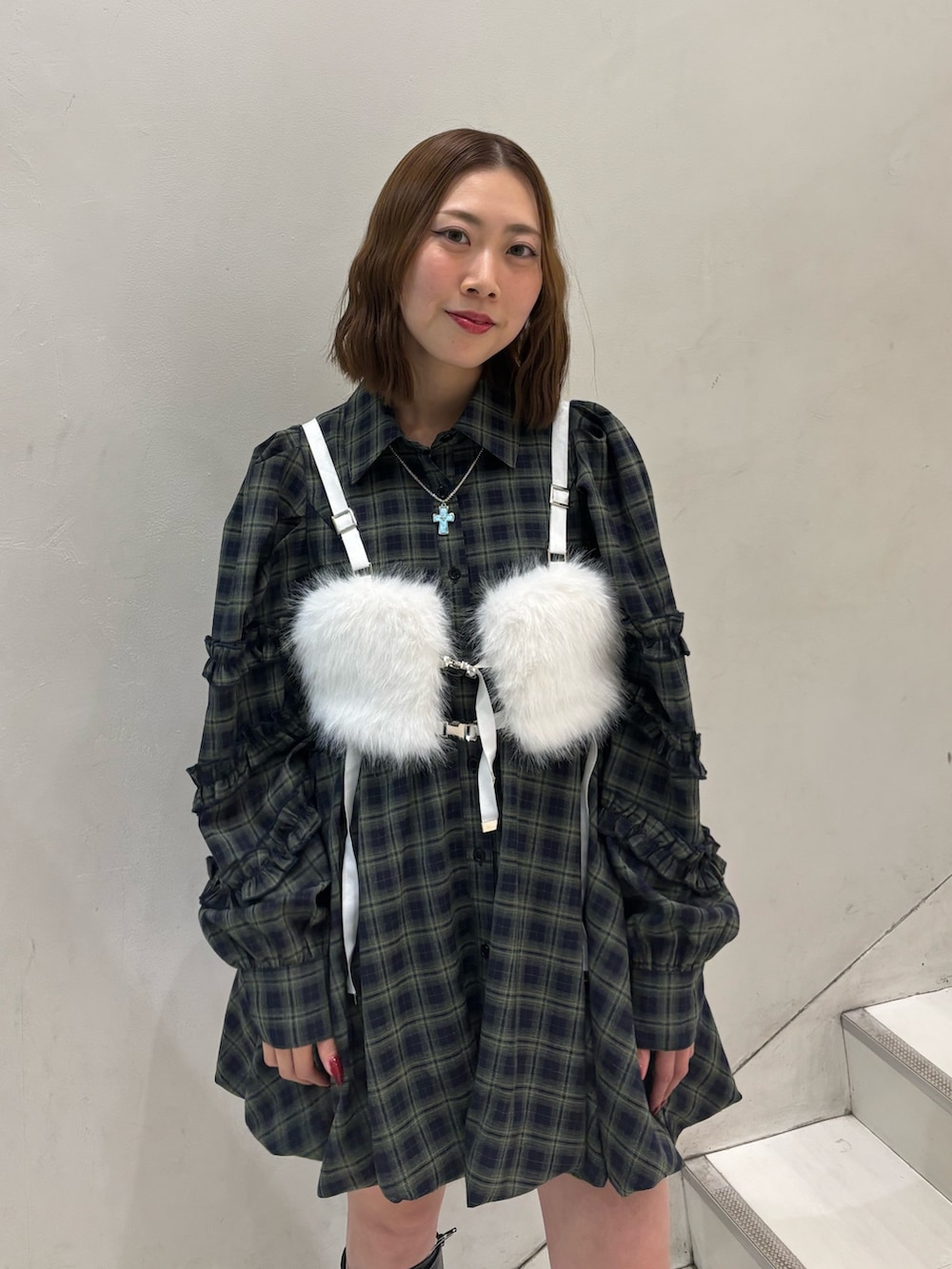 グリーン系のワンピース、ブラック系のブーツ、ホワイト系のベルトを着用したレディースの冬コーディネートの5枚目の写真