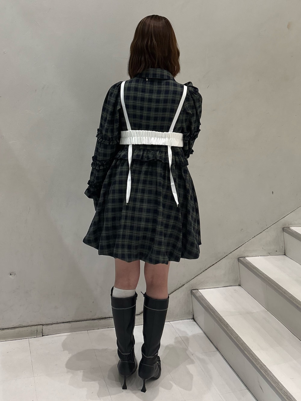 グリーン系のワンピース、ブラック系のブーツ、ホワイト系のベルトを着用したレディースの冬コーディネートの4枚目の写真