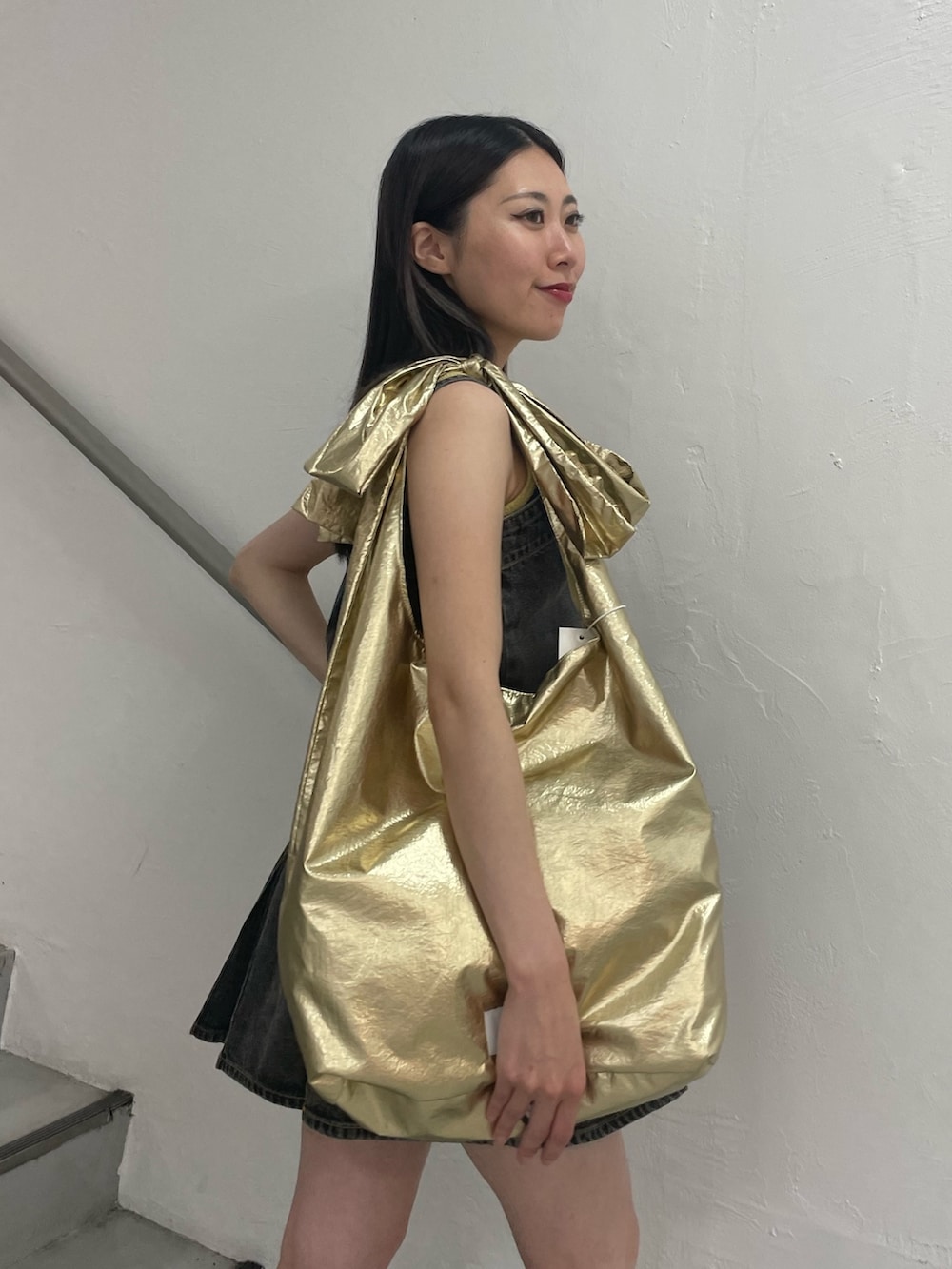 ブラック系のワンピース、イエロー系のタンクトップ、ゴールド系のトートバッグを着用したレディースの夏コーディネートの5枚目の写真